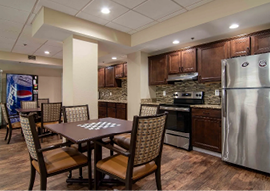 A kitchen with a dining table and chairs, a refrigerator, and a microwave. AI generated content